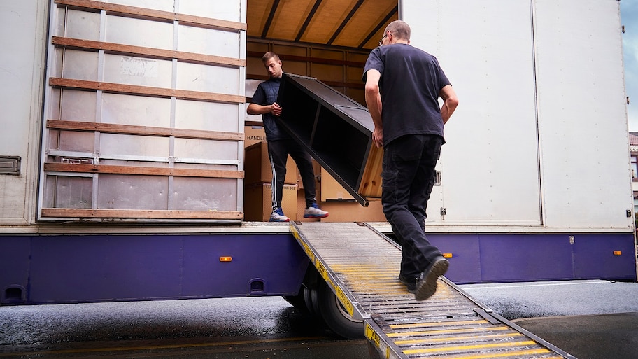 Employees of a moving company loading with furniture a truck