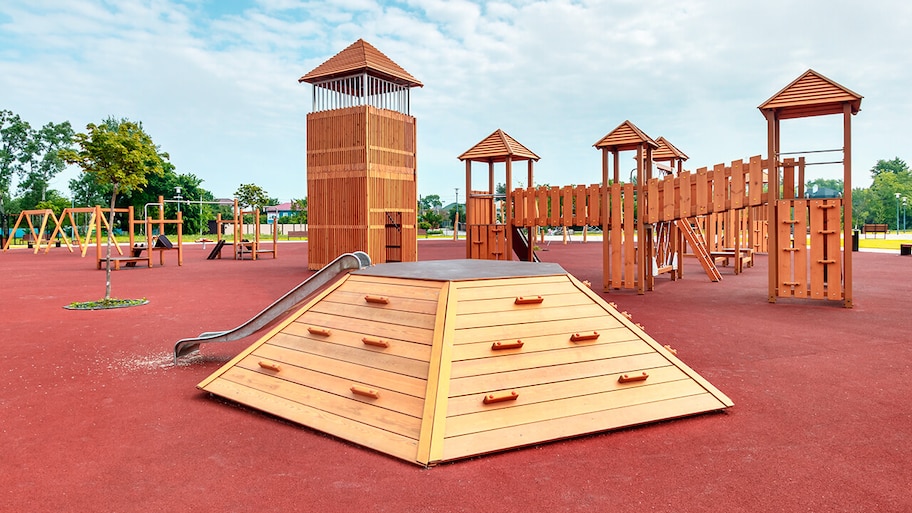 playground with poured red rubber surface and wooden structures